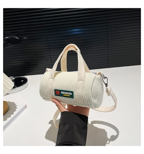 Close-up of off-white corduroy cylindrical bag with green label and silver hardware