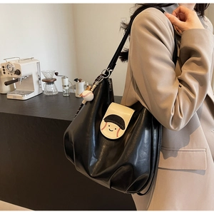 Detail of black Hobo tote bag featuring baseball patchwork and sports charms