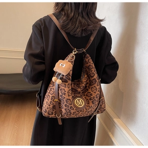 Detail of leopard print tote bag with golden metal M logo and plush bear keychain