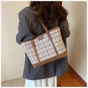 Brown and white plaid tote bag shown on a model wearing a grey blazer and white skirt