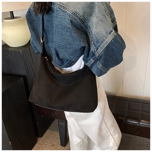 Detail der schwarzen matten Hobo-Tasche mit goldenen Beschlägen an einem eleganten Schultergurt