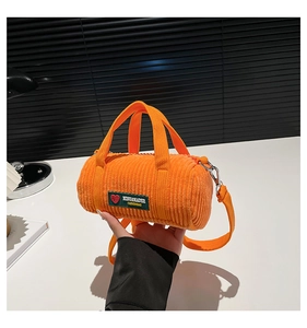 Detail of orange corduroy cylindrical bag showing ribbed texture and brand label