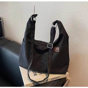 Détail du sac cabas noir en toile montrant la bandoulière réglable et l'étiquette logo
