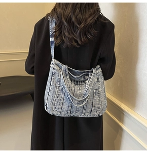 Detail of washed denim tote bag showing vintage stitching and adjustable shoulder strap