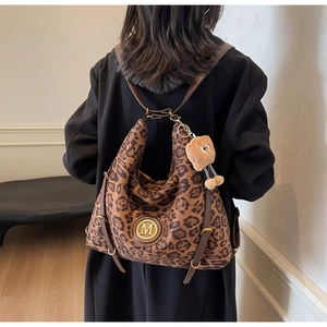 Detail of leopard print tote bag with gold metal logo and plush bread charm pendant