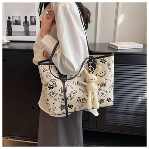 Detail of off-white tote bag with black graffiti print and plush bunny keychain