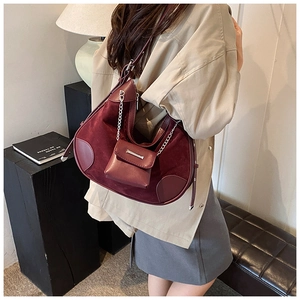 Detail der burgunderroten Halbmond-Schultertasche mit mattem Finish und Ketten-Minianhänger