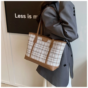 Close-up of vintage plaid tote bag with brown leather trim and metallic brand logo