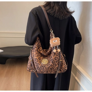 Detail of hobo bag featuring brown leopard print, gold M logo and plush charm