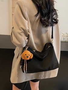 Black hobo shoulder bag with brown plush dog charm shown on a model in a minimal setting