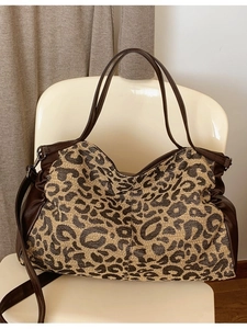 Large leopard print tote bag with brown leather straps displayed on a chair