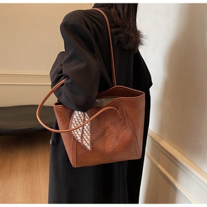Detailansicht braune Leder-Tragetasche mit dekorativem geometrischem Seidenschal