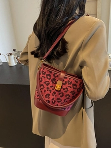 Borsa a secchiello bordeaux leopardata con fibbia dorata indossata da modella