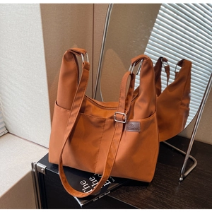 Détail du sac fourre-tout en nylon orange avec poches avant et anneaux métalliques