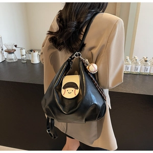 Detail of black PU leather backpack with baseball smiley patch and decorative charm