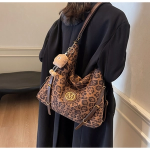 Detail of leopard print hobo bag featuring a gold M logo and cute plush bear charm