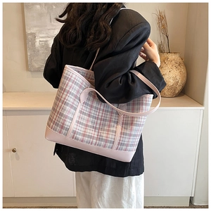 Detailed view of pink plaid tote bag with leather straps on a model's shoulder