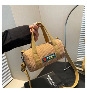 Detail of ginger yellow corduroy cylinder bag with embroidered fashion tag and wide strap