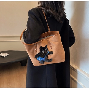 Detailed view of brown tote bag with fuzzy black cat embroidery and blue fish pouch