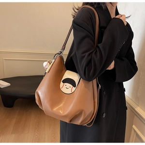 Detail view of the baseball theme leather bucket bag with cartoon face flap and sports charm