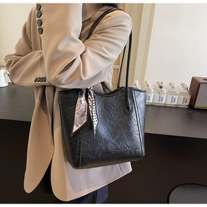 Detail einer großen schwarzen Ledershopper mit Seidenschal an Khaki-Anzug-Modell