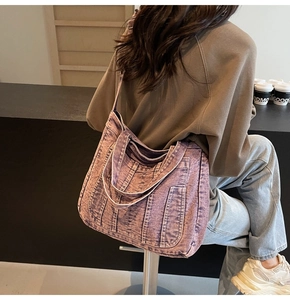 Detailed view of the purple washed denim tote bag texture and functional side pockets