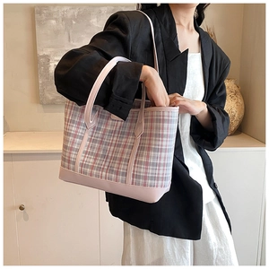 Detailed close-up of pink and white checkered woven tote bag with smooth leather trim