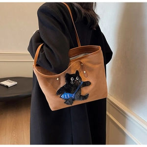 Detail of caramel brown suede tote bag with cartoon cat patch embroidery and blue fish pouch