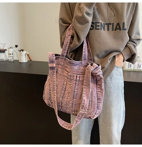 Detail of purple acid-wash denim tote bag featuring multi-pocket design and crossbody strap