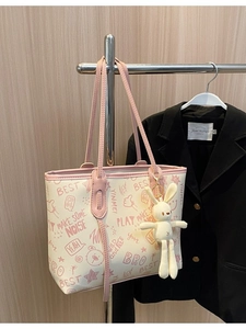 Graffiti print tote bag with pink handles and rabbit plush keychain on a hanger