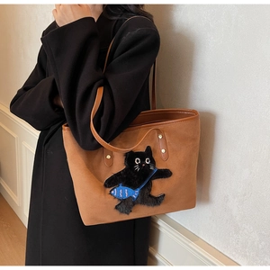 Detail of a brown suede tote bag featuring a cute black cat and small blue fish embroidery