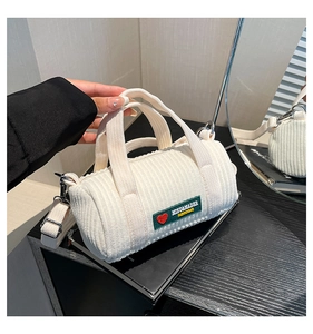 Detailed view of white corduroy cylinder bag featuring green logo tag and texture