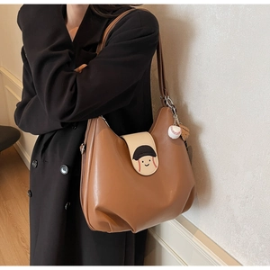 Detail of vintage brown leather bag with cartoon baseball flap and sports charms