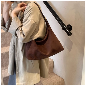 Dunkelbraune Hobo-Tasche aus mattem Wildleder an der Schulter mit beigem Trenchcoat