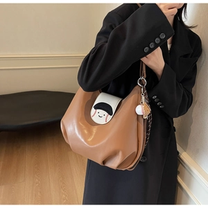 Detail of caramel PU leather bag with cartoon embroidery and mini baseball charm
