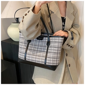 Close-up of the black and white plaid tote bag with premium leather trim and brand logo