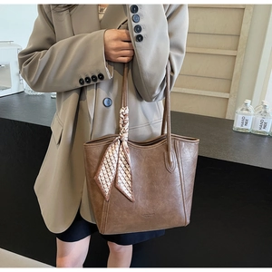 Detail der dunkelbraunen Leder-Tote mit „Fashion trend“-Text und gemustertem Seidenschal
