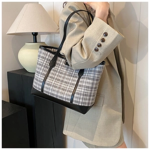 Detail of the vintage plaid tote bag featuring premium black leather straps and stitching