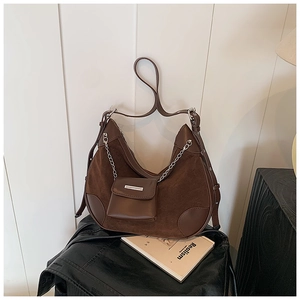 Detail einer dunkelbraunen Wildleder-Hobo-Tasche mit Metallkette und kleiner Münzbörse