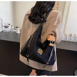 Detail of vintage black corduroy tote bag featuring a gold M logo and a cute gingerbread man charm