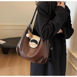 Close-up of brown pleated bucket bag with cartoon baseball character on model shoulder