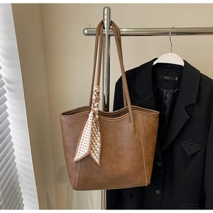 Detailansicht der braunen Leder-Tragetasche mit elegantem kariertem Seidenschal-Dekor