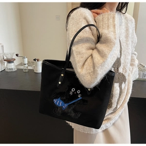 Detail of a large black canvas tote bag featuring a cute 3D black cat embroidery applique