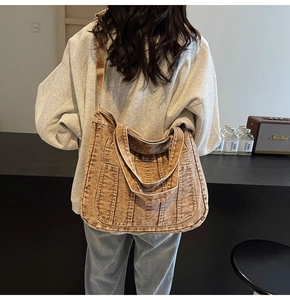Back view of a large vintage washed denim tote bag shown with model for size reference