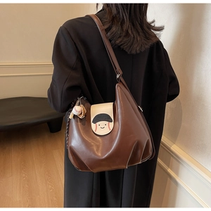 Brown soft leather tote with smiley face and baseball pendant shown on a model