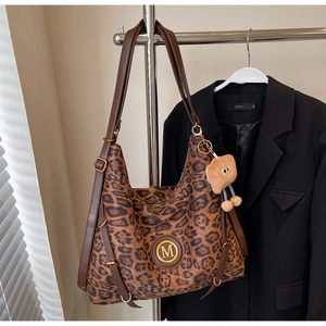 Detailed view of leopard print tote bag with brown leather strap and gold M logo