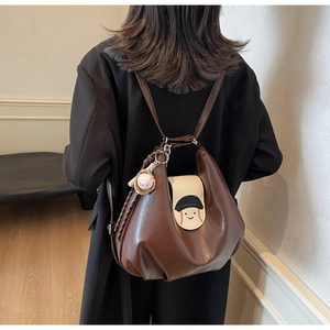 Detail view of a vintage dark brown leather backpack featuring a cute character flap design
