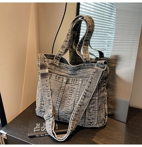Close-up of distressed grey denim tote bag with wide handles and adjustable silver buckle strap