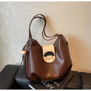 Detailed shot of brown vintage shoulder bag with baseball smiley flap and ball keychain