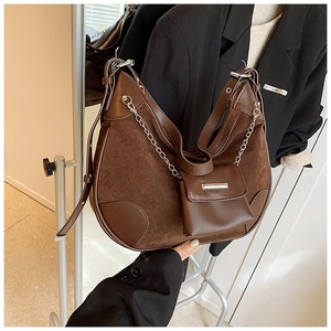 Details einer braunen Vintage-Hobotasche mit Silberkette und kleinem Taschen-Accessoire